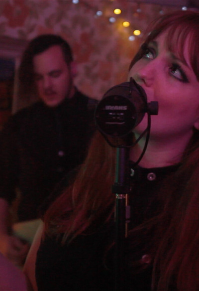 chanteuse d'un groupe de musique en live dans décor rétro avec bassiste en arrière plan