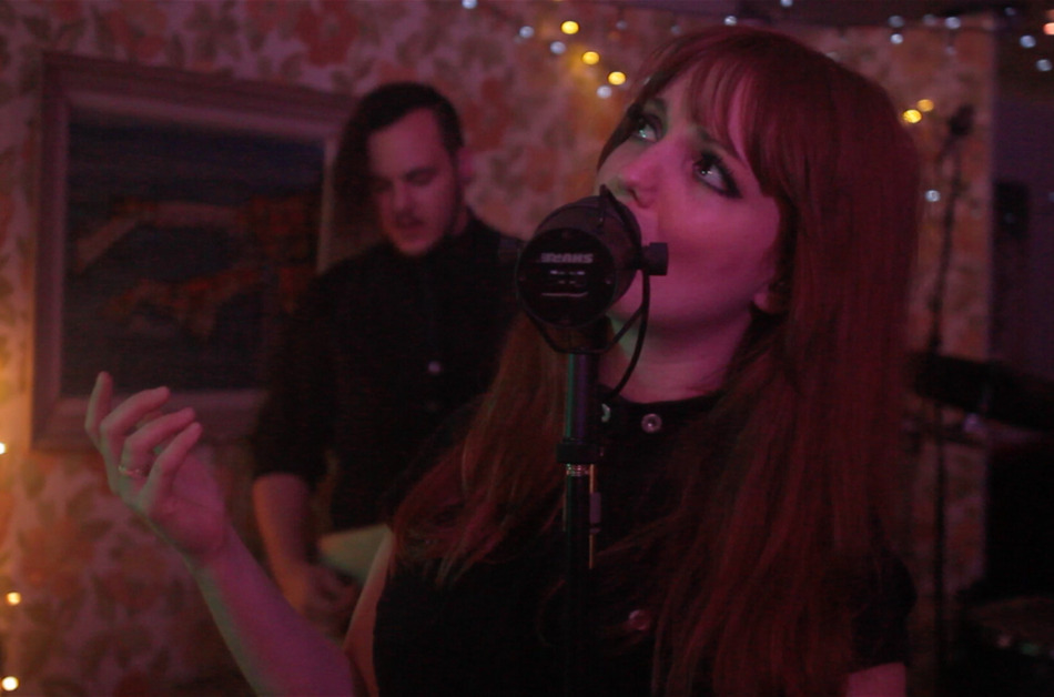 chanteuse d'un groupe de musique en live dans décor rétro avec bassiste en arrière plan